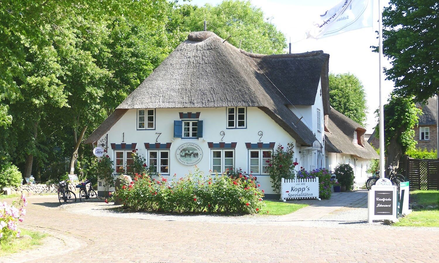 En traditionel bygning med stråtækt tag, nummererede vinduer og et skilt, der angiver, at det er en restaurant.