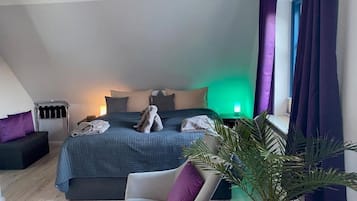 Ein modernes Schlafzimmer mit einem Bett, einem Sessel, einem Nachttisch und einer Pflanze.