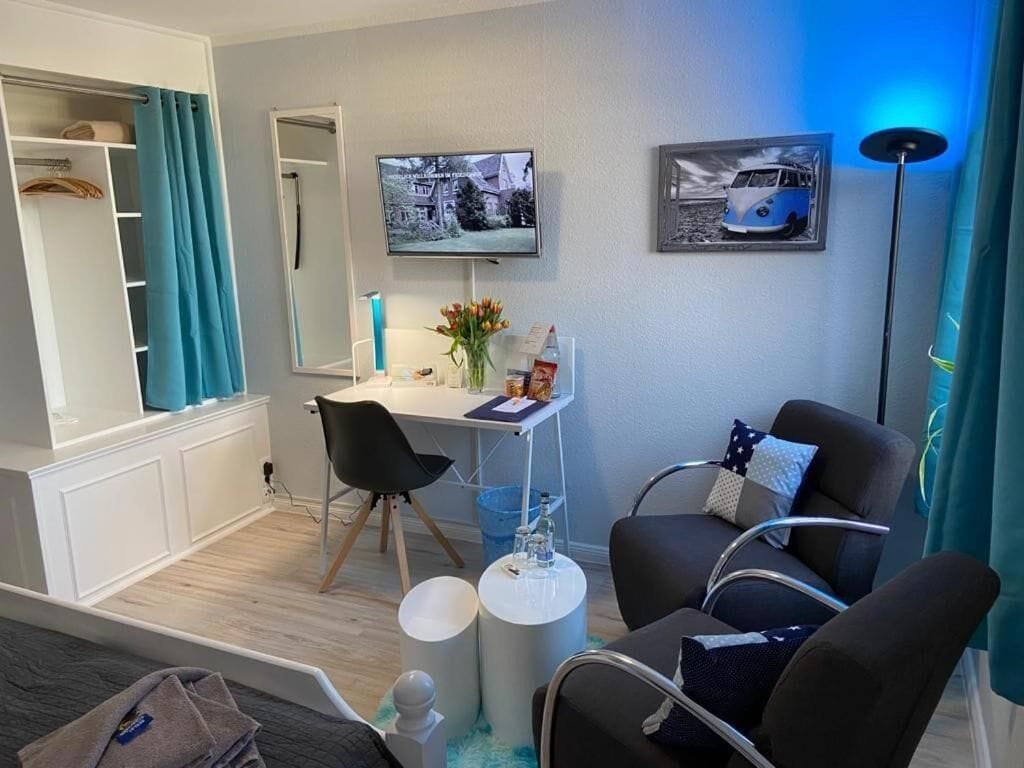 Une chambre moderne équipée d’un bureau, de deux chaises, d’une télévision et d’un lit.