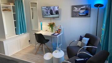 Une chambre moderne équipée d’un bureau, de deux chaises, d’une télévision et d’un lit.