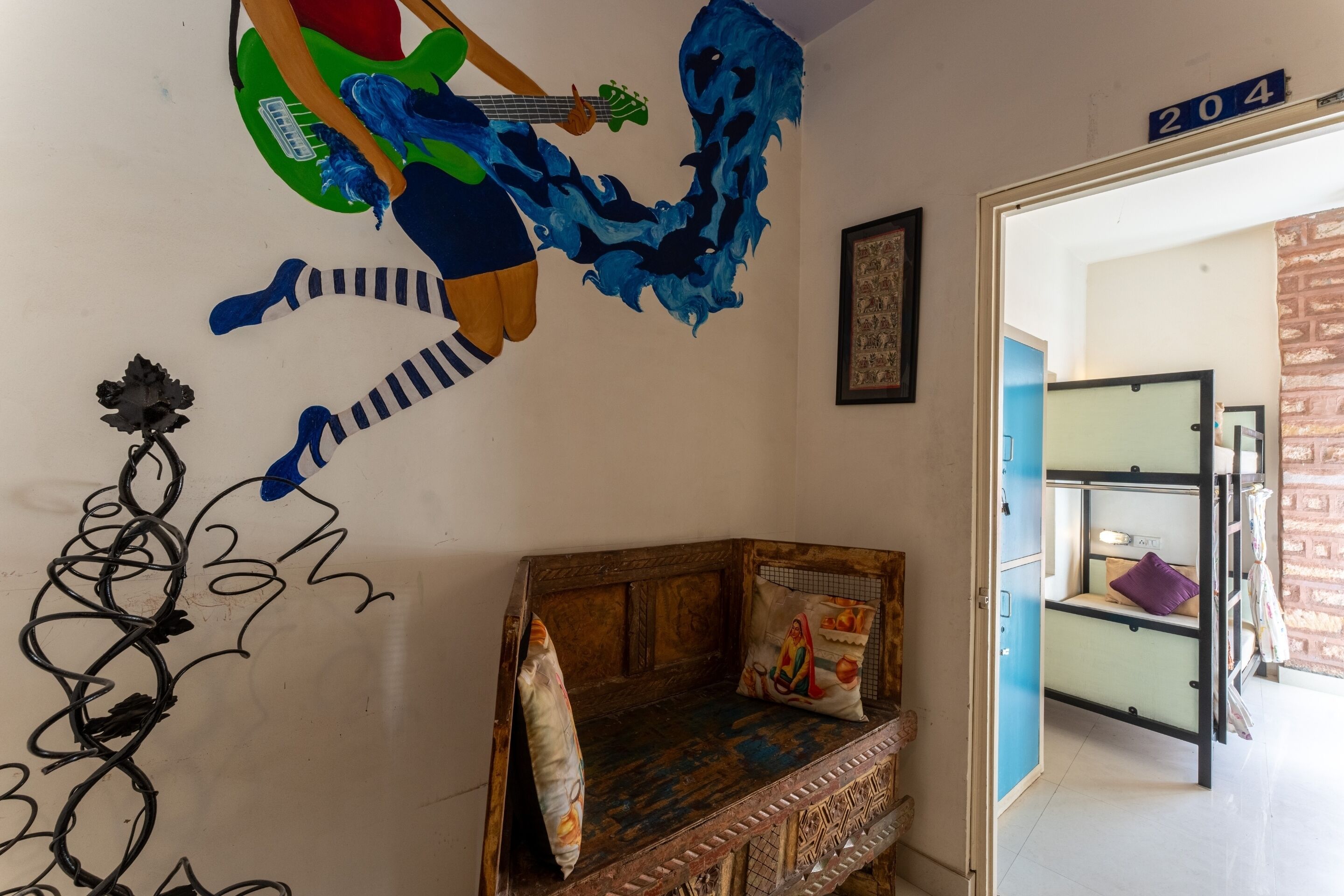 A room with a wooden bed, a blue and green guitar mural, a number '204' sign, and a brick wall.