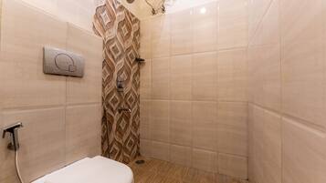 Un baño con ducha, inodoro y panel de control.