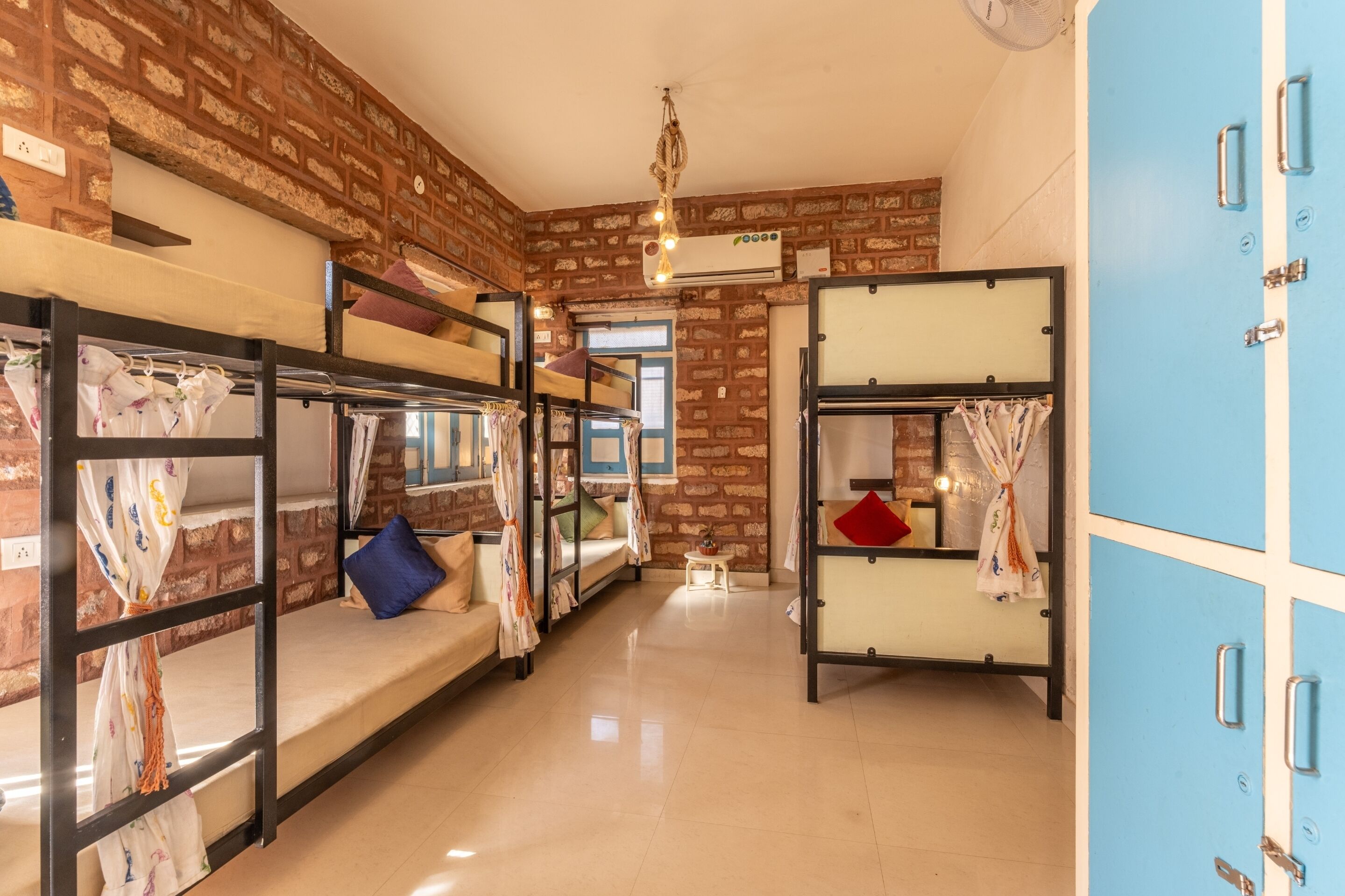 Un dormitorio con literas, una pared de ladrillo, un ventilador de techo y una ventana.