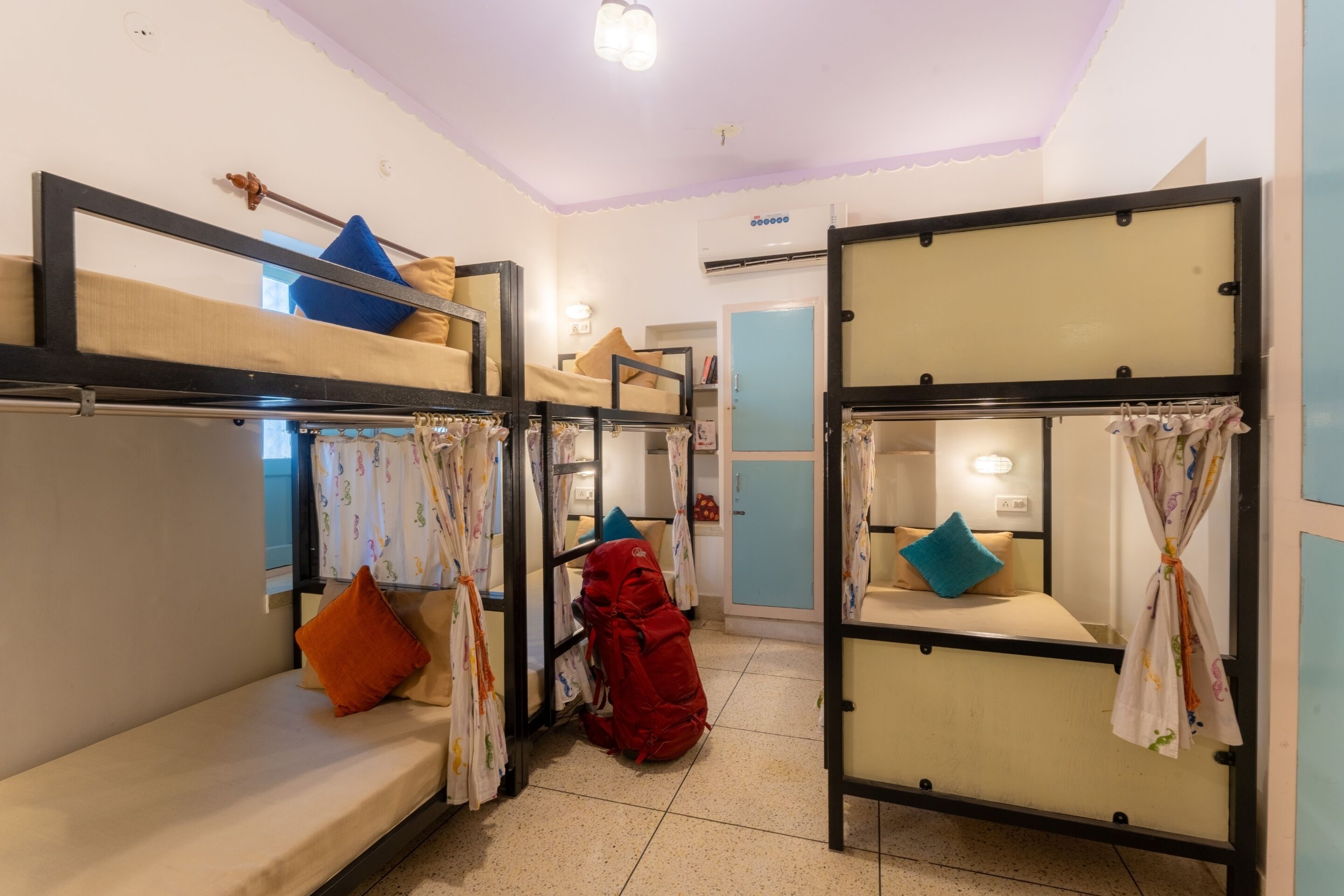 A dormitory room with bunk beds, a wardrobe, and a small seating area.