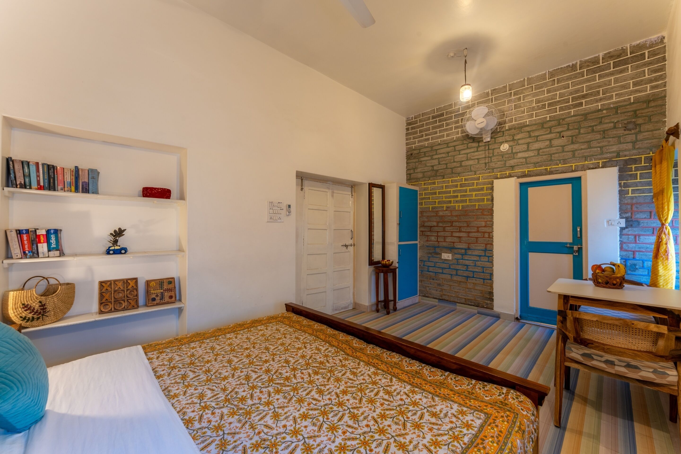 Una habitación con una cama, una estantería, un escritorio y una pared de ladrillo.