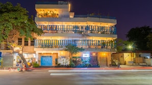 Un hotel de varios pisos con balcones, una entrada a nivel de calle y una fachada bien iluminada.