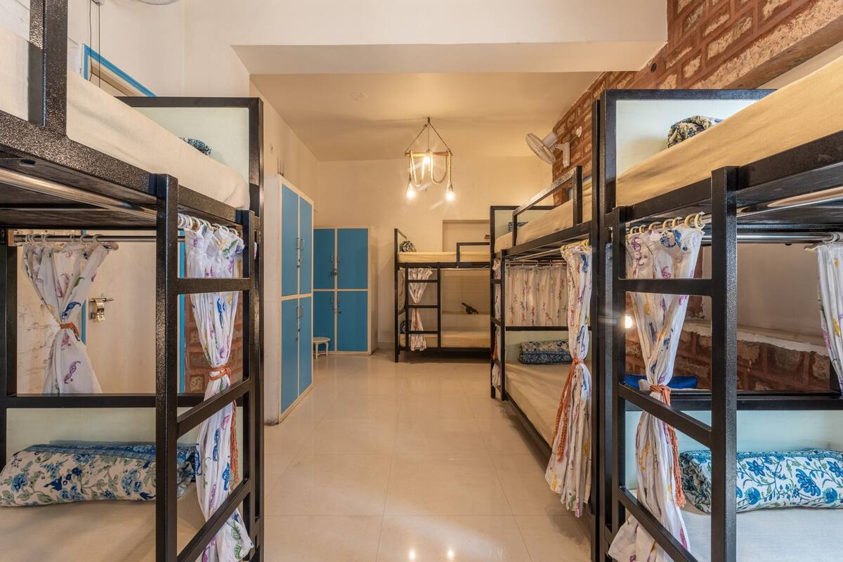 Un couloir avec des lits superposés, une armoire bleue et un luminaire suspendu.