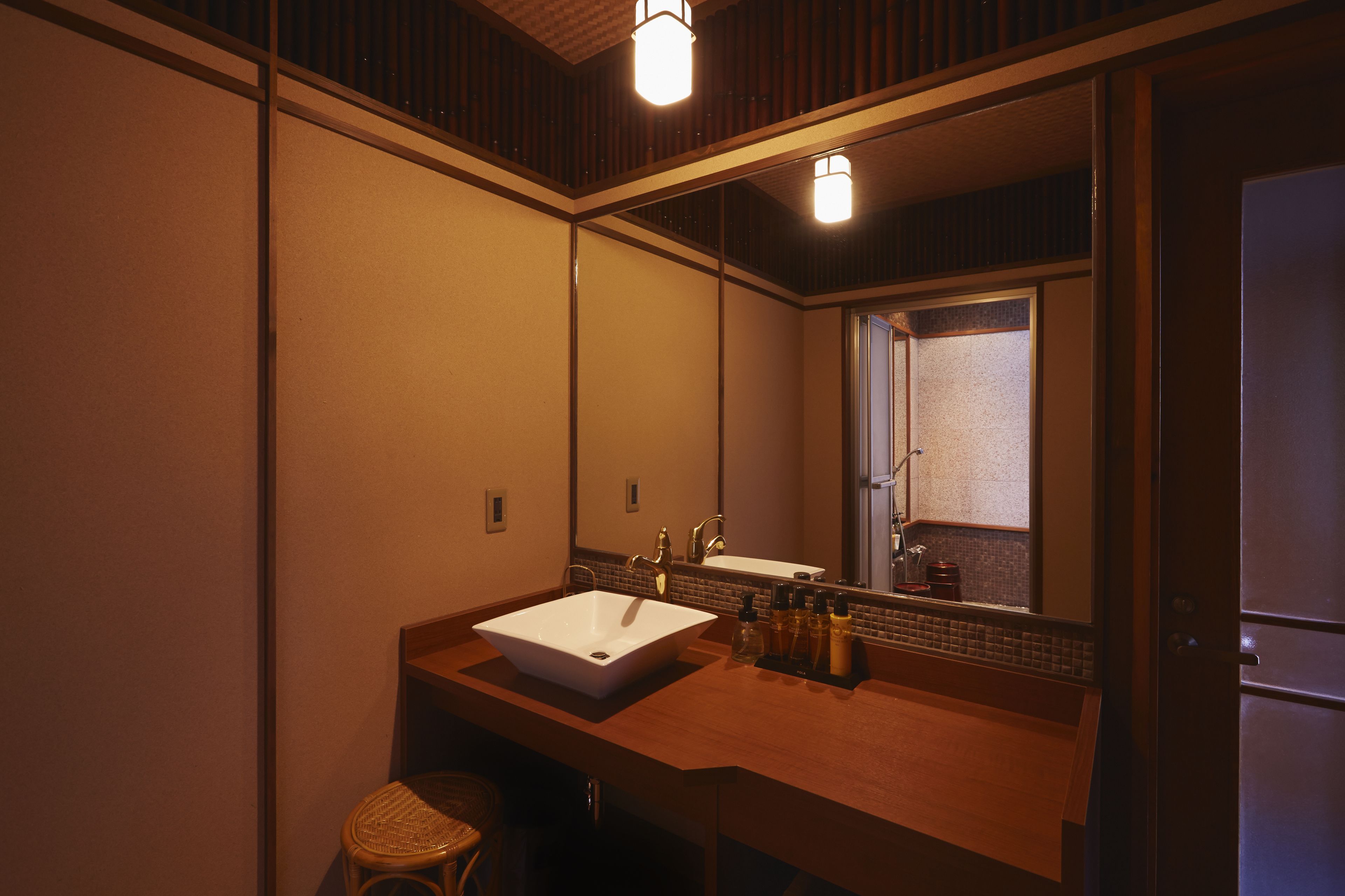 A bathroom with a large mirror, a white sink, and a wooden vanity.