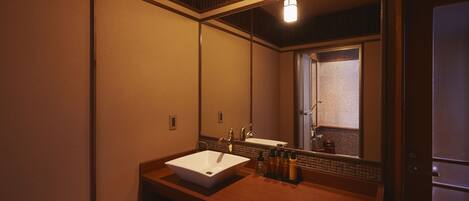 A bathroom with a large mirror, a white sink, and a wooden vanity.