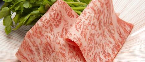 A plate with sliced meat and green herbs.