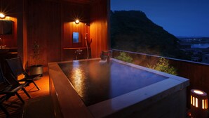 Un espace de détente en bois comprenant un jacuzzi, des sièges et une vue sur le paysage.