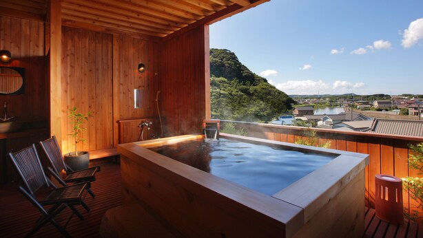 Un espace de détente en bois comprenant un jacuzzi, des sièges et une vue sur un lac et des montagnes.