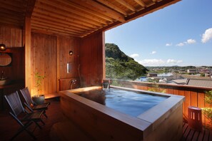 A wooden spa area with a hot tub, seating, and a view of a lake and mountains. - Sanbi no yado Ryokan Kawana (Kimitsu)