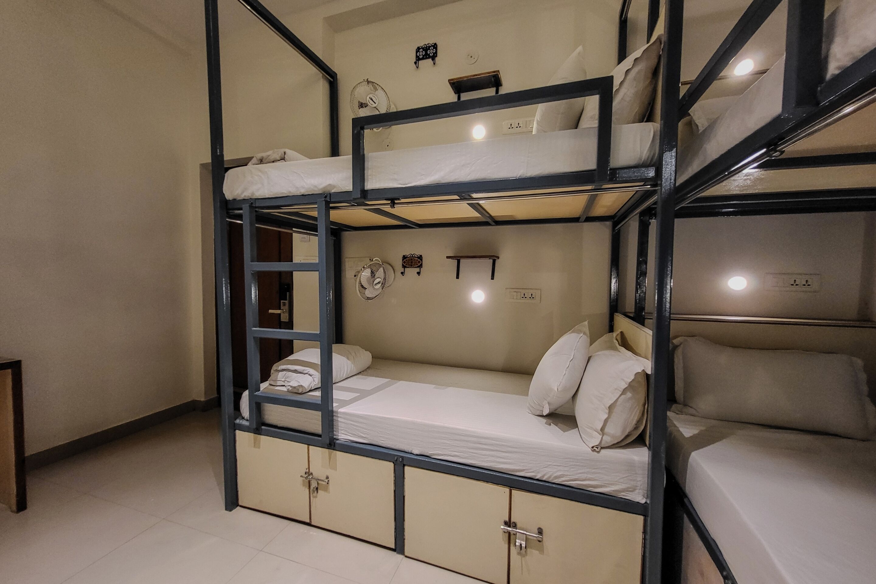 A bunk bed room with a ladder, a shelf, and a small desk.