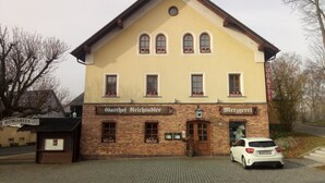 A two-story building with a brick facade, a sign reading "Gasthof Reichsadler," and a parked white car in front. - Landgasthof Reichsadler (Hoechstaedt im Fichtelgebirge)