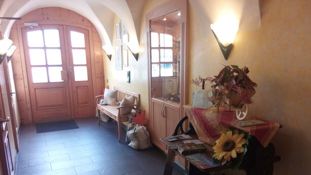 A hallway with wooden flooring, a bench, a table with a sunflower, and a wall-mounted light fixture. - Landgasthof Reichsadler (Hoechstaedt im Fichtelgebirge)
