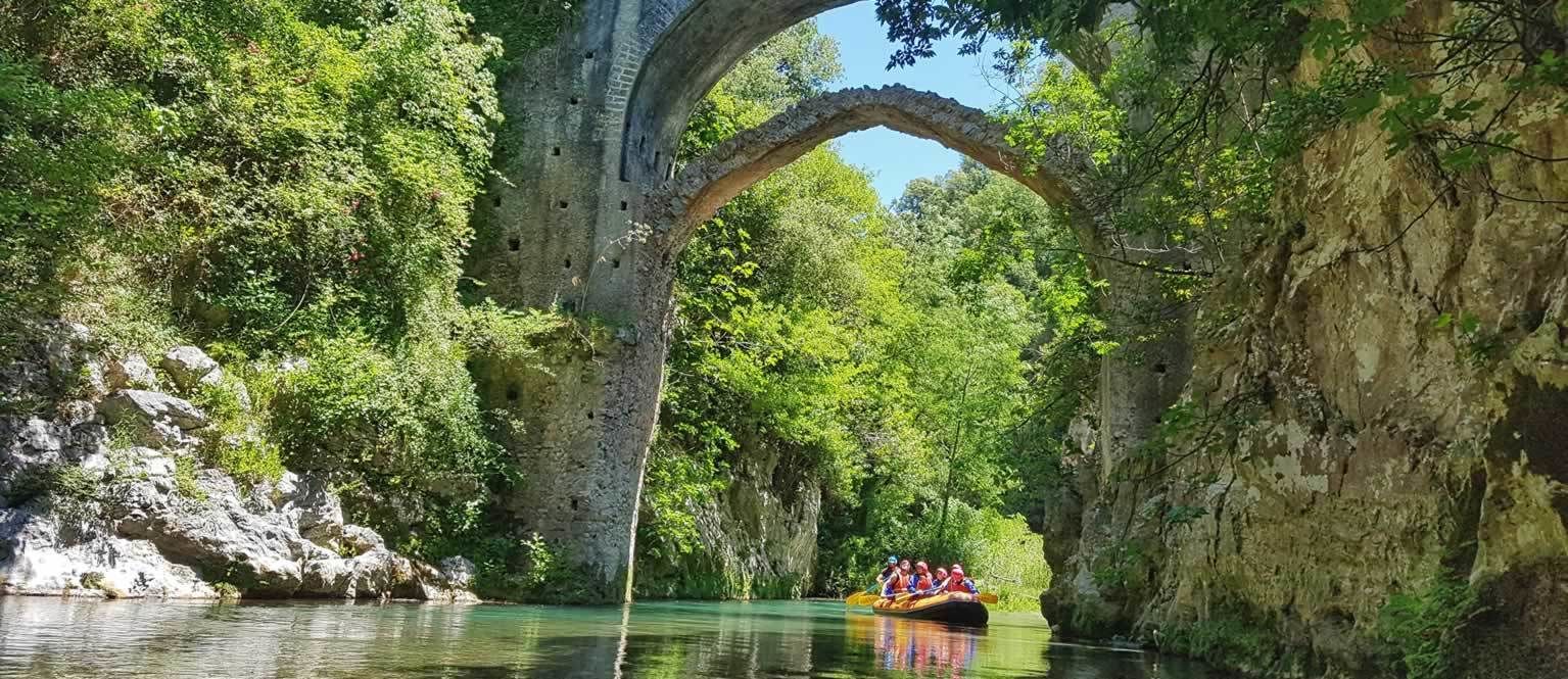 Une rivière traversée par un pont de pierre, entourée de verdure.
