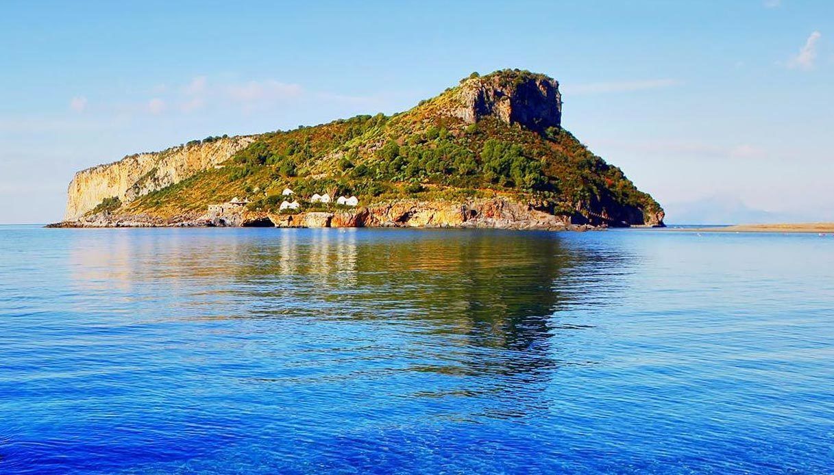 Una isla costera con una colina rocosa destacada y algunos edificios en su ladera.