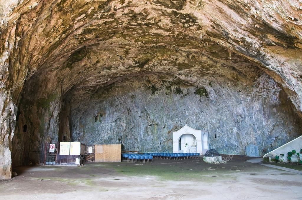 A cave-like interior with a small altar and rows of blue chairs.