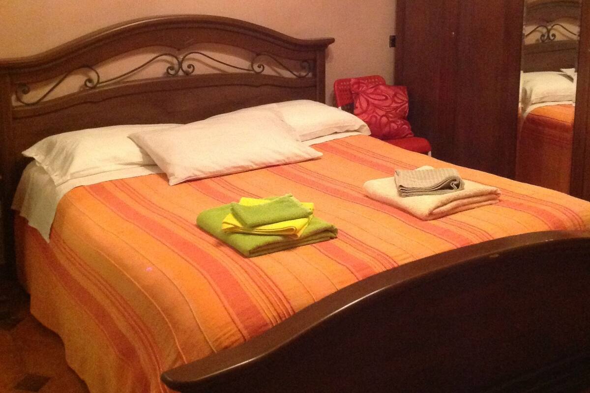 A neatly made bed with a striped bedspread, pillows, and folded towels.