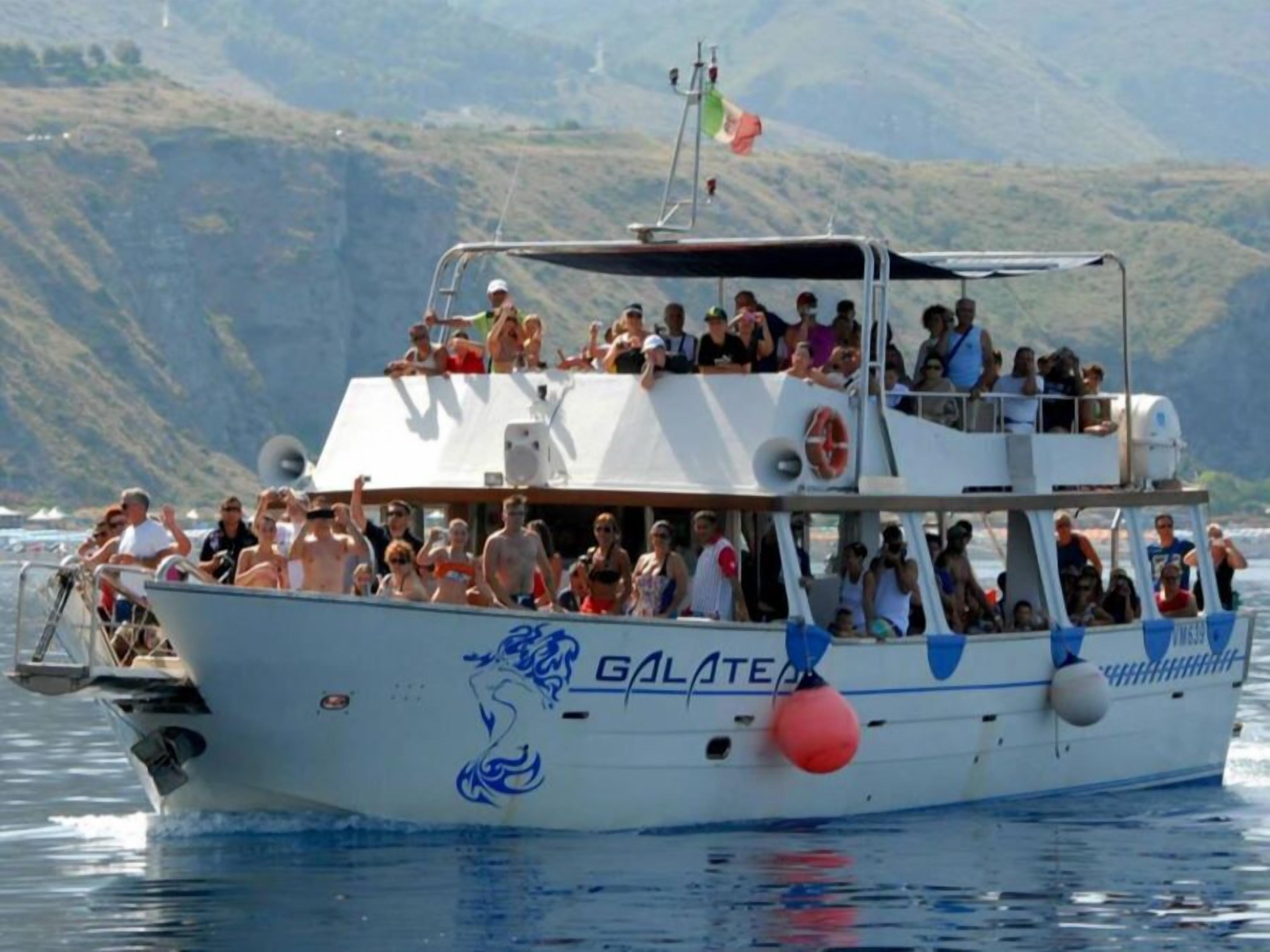 Un barco con el nombre "GALATEA" en su costado, transportando pasajeros.
