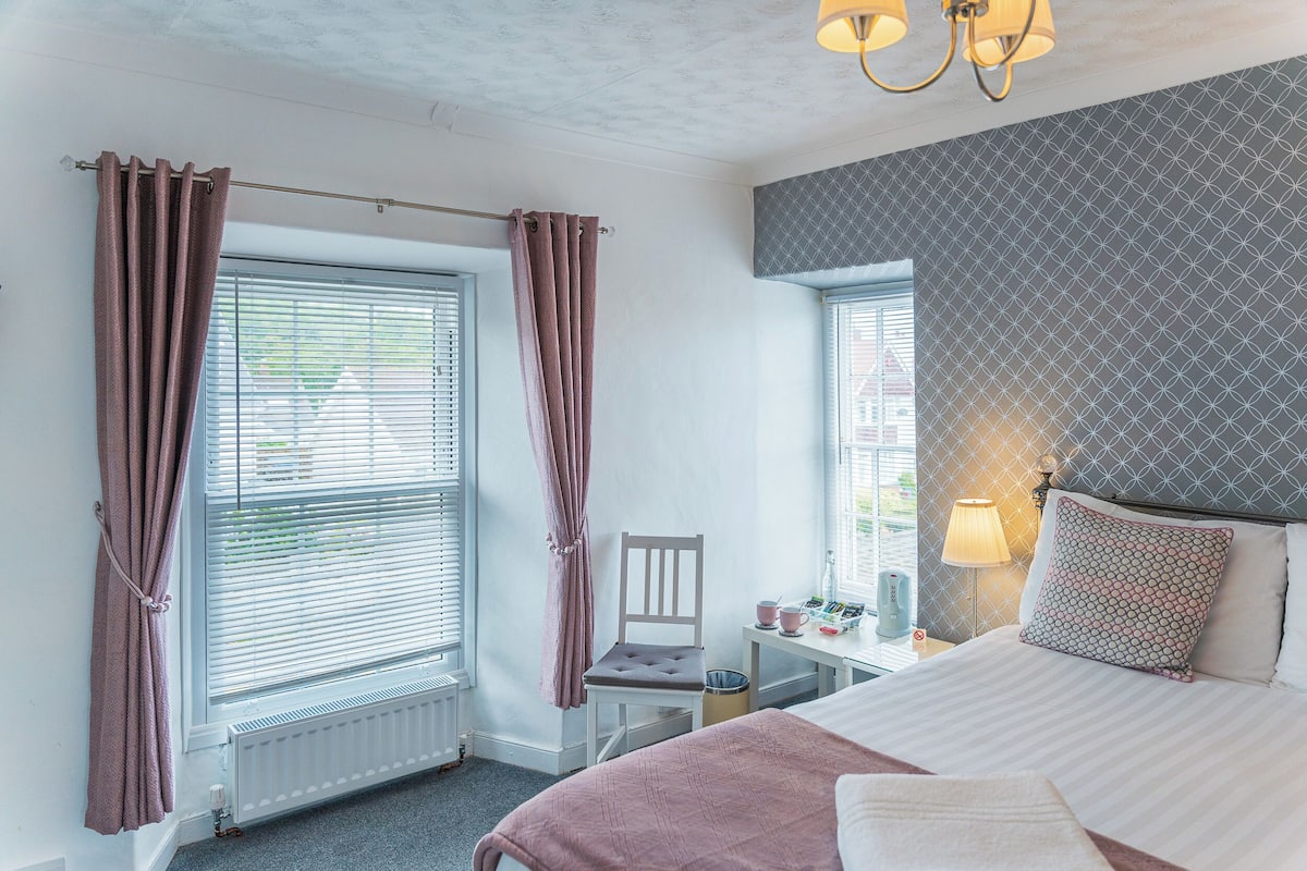 A bedroom with a bed, a chair, a desk, a lamp, and a radiator.