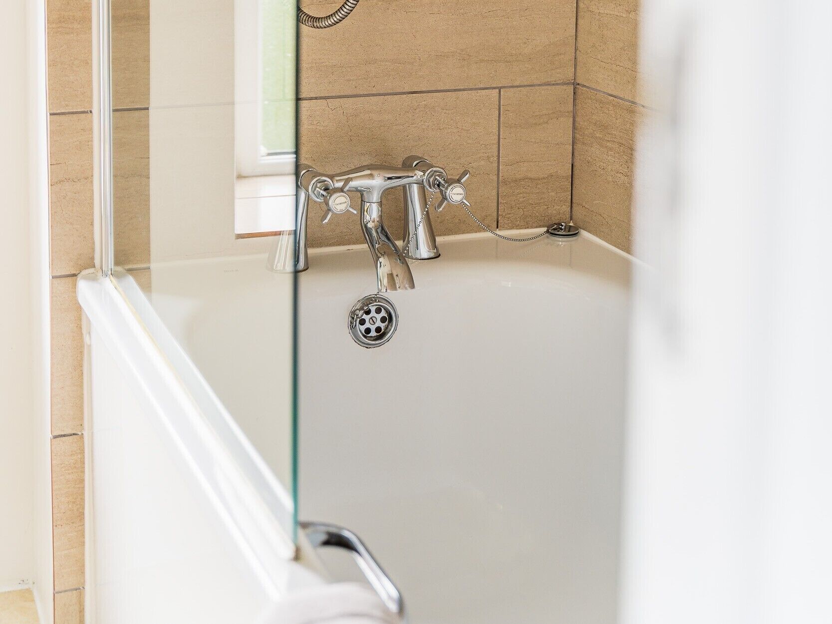 Un baño con bañera, ducha y puerta de cristal.