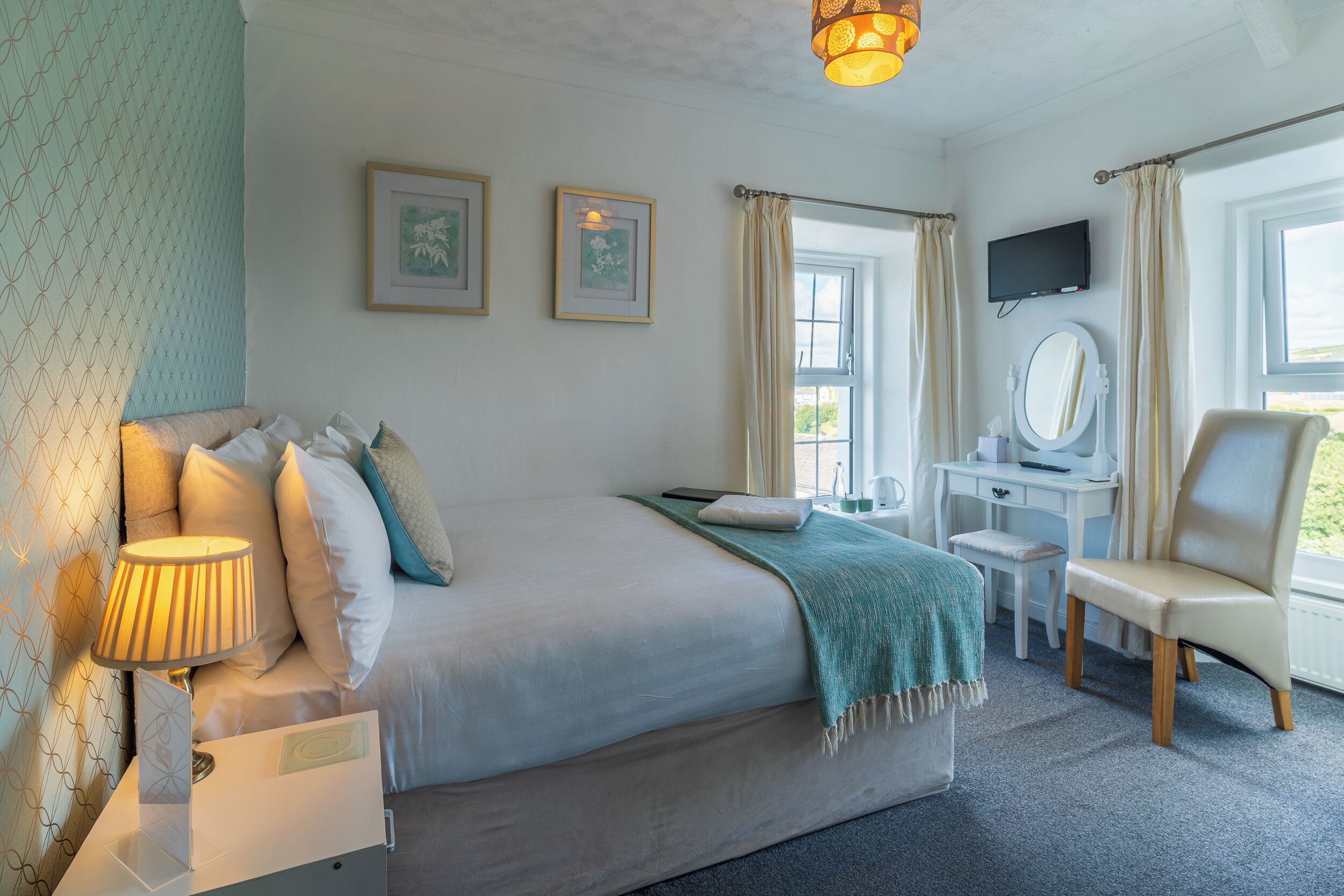 Une chambre bien rangée, avec un lit, une table de chevet, une lampe, une chaise, un bureau et un téléviseur.