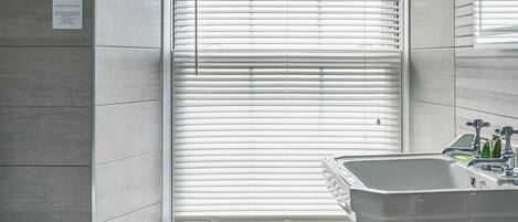 A bathroom with a toilet, sink, and window with blinds.