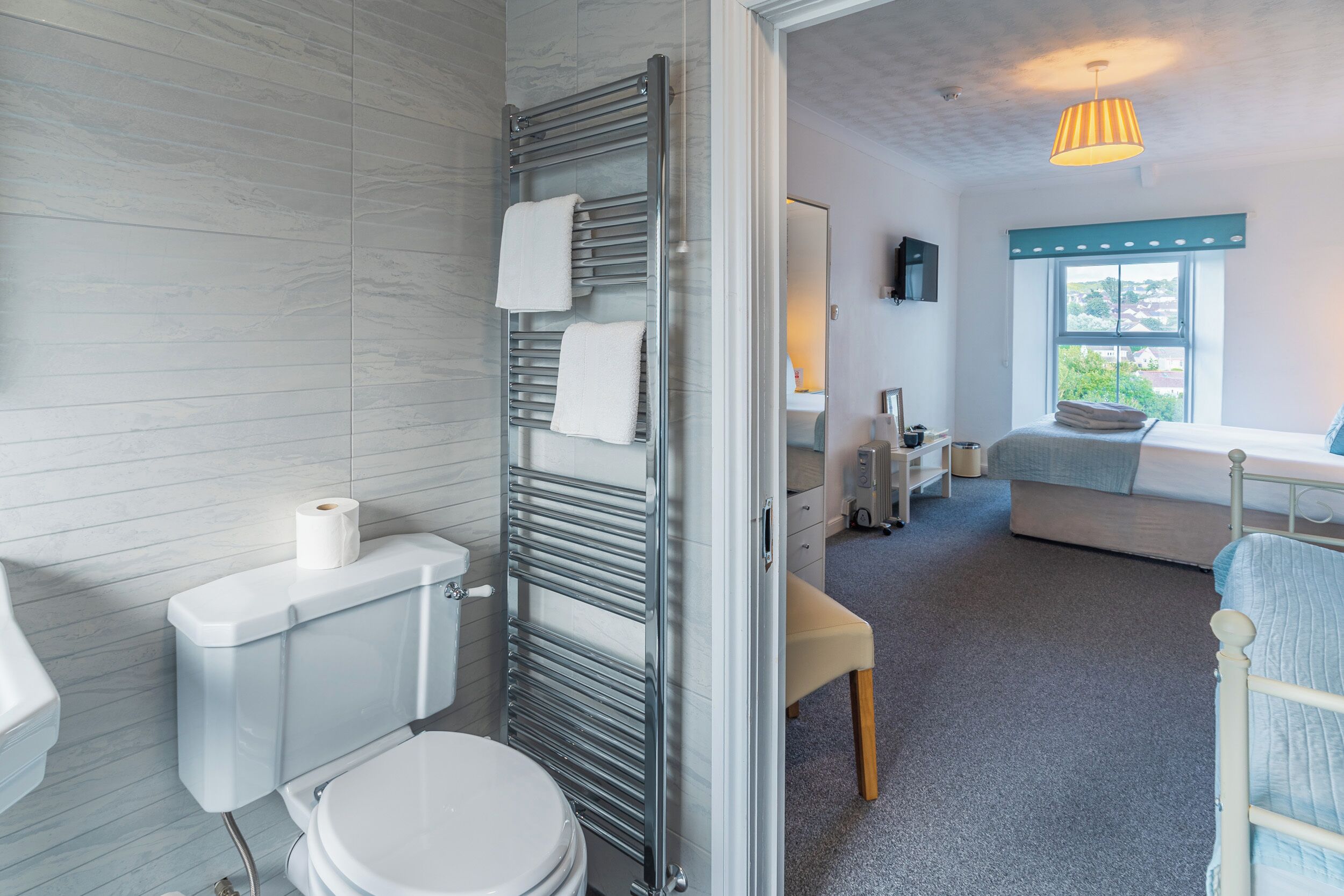 A modern bathroom with a toilet, a towel rack, and a visible toilet paper roll.