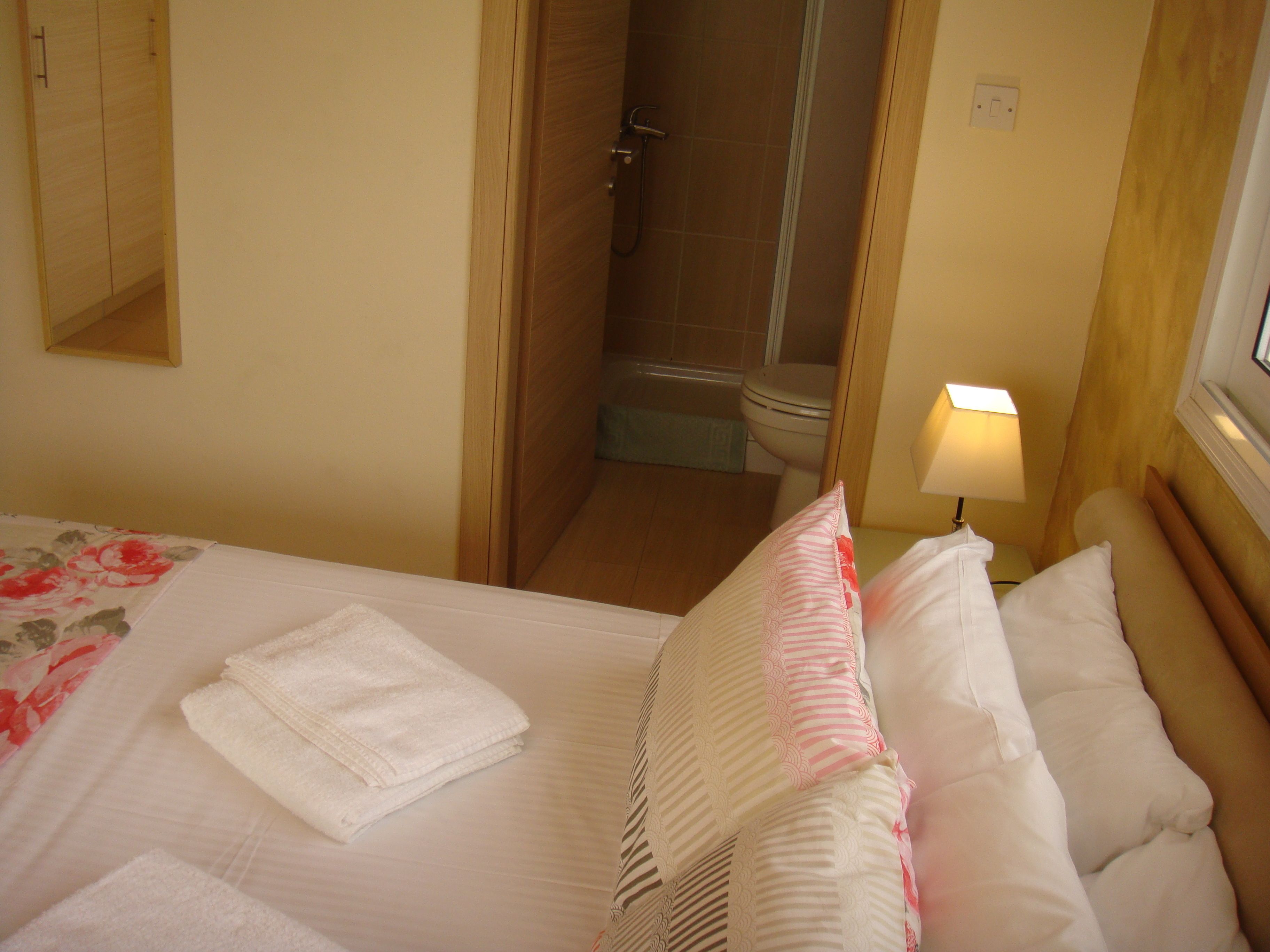 Een hotelkamer met een bed, een badkamer en een nachtkastje met een lamp.