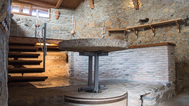 A stone-walled room with a stone table, wooden steps, and a hanging rope system. - CR La Flor del Naranjo (Cadalso)