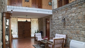 A spacious indoor area with a stone wall, wooden furniture, and a white radiator. - CR La Flor del Naranjo (Cadalso)