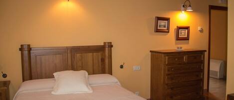 A bedroom with a wooden bed, a dresser, and wall-mounted lamps.