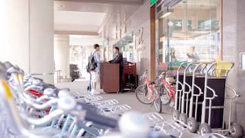 A bike rental station with multiple bicycles and a red bicycle parked next to a building with a sign.