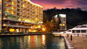 A multi-story hotel with balconies, a waterfront view, and a dock with boats. - Hotel Del Lago (Yuchi)