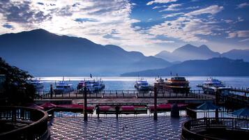A marina with boats docked, a pier with a patterned floor, and mountains in the background.