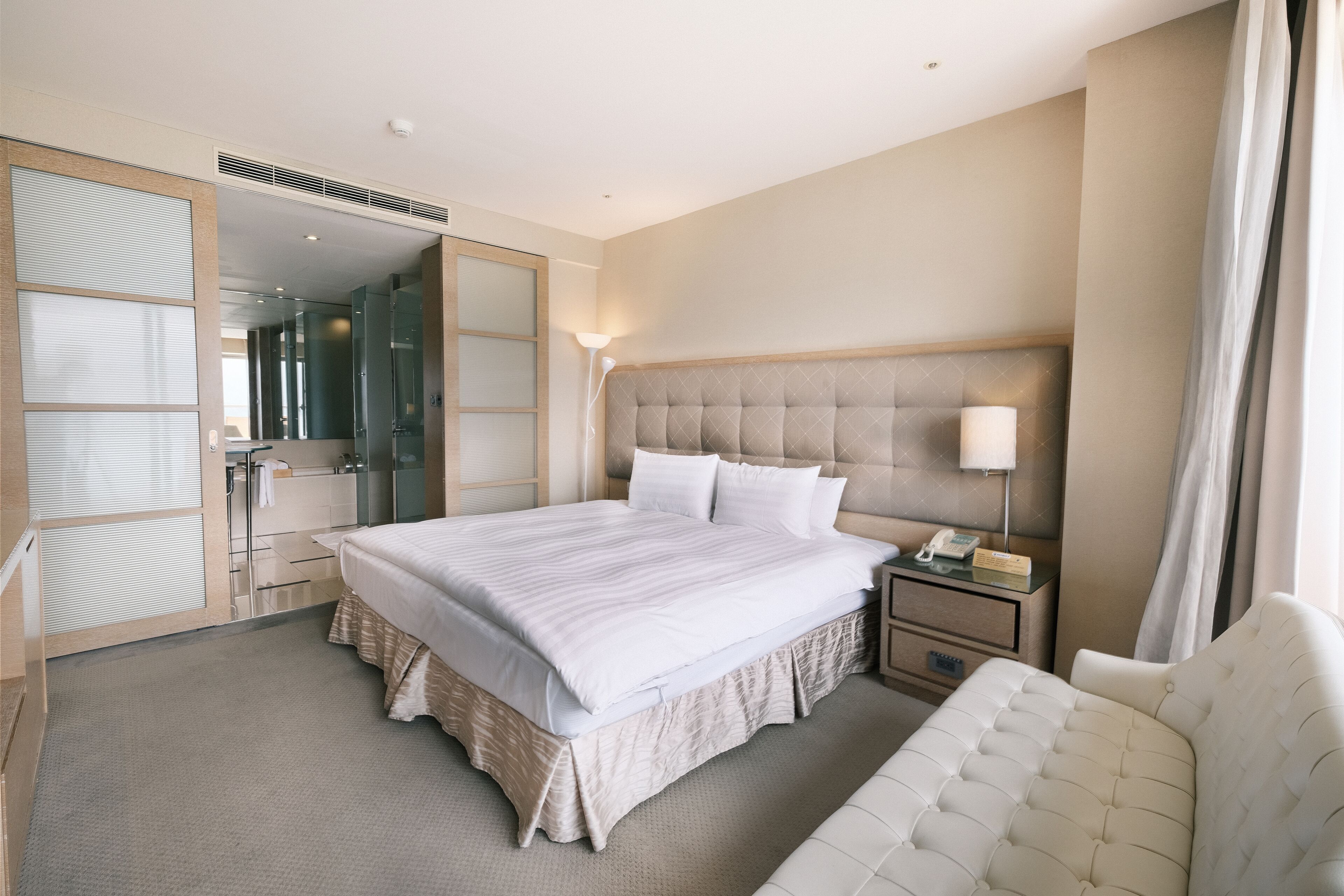 Una habitación de hotel moderna con una cama grande, una mesita de noche y una silla.