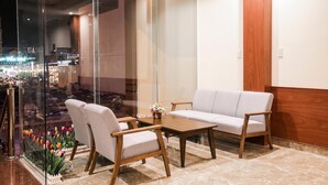 A modern lobby with a glass wall offering a view of a busy street at night. - Quy Nhon Blue Sea Hotel (Quy Nhon Nam)