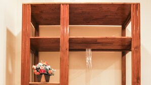 A wooden wardrobe with multiple shelves, a hanging rod, and a folded towel on the bottom shelf. - Quy Nhon Blue Sea Hotel (Quy Nhon Nam)