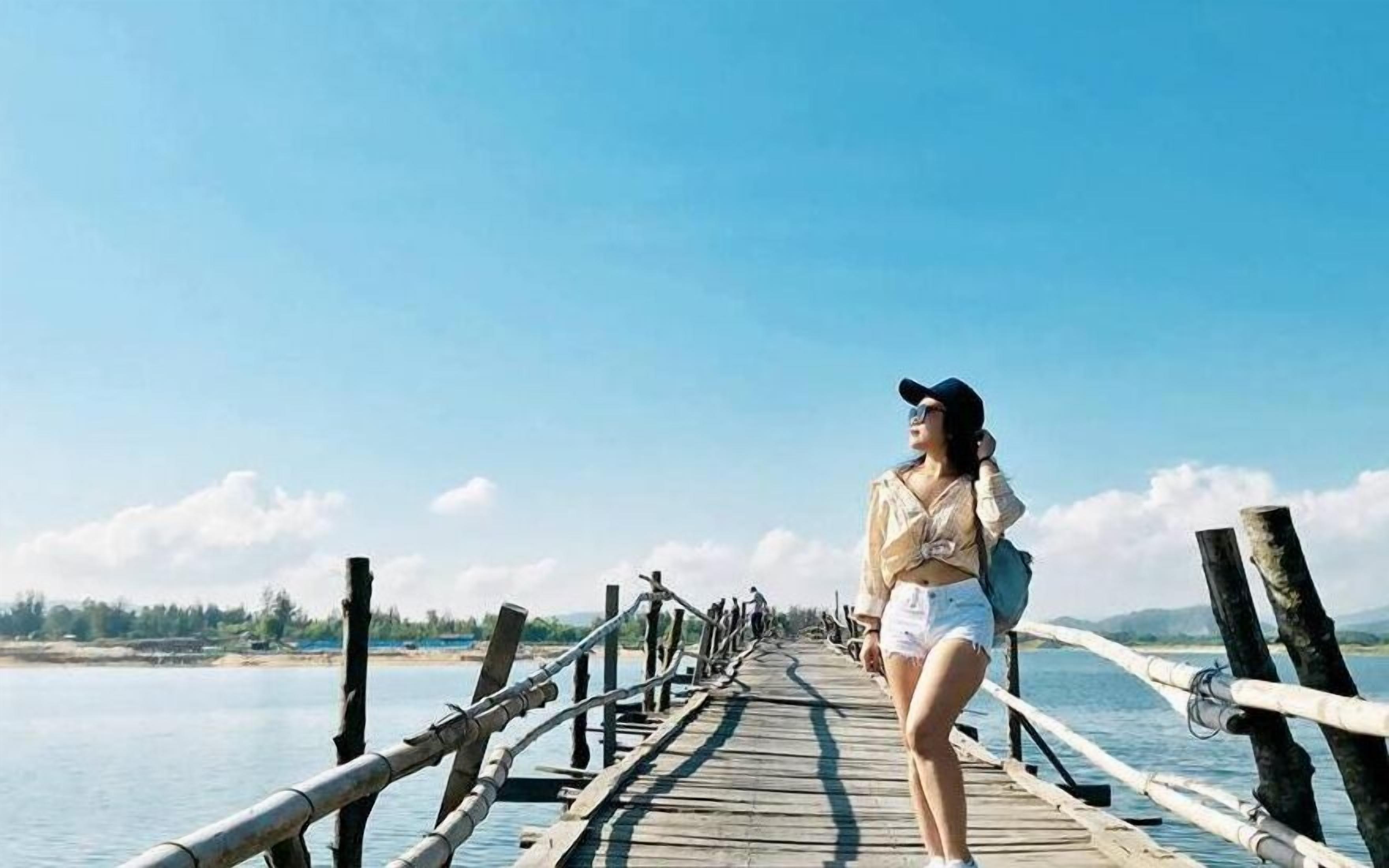A wooden pier extending over calm water with a clear sky.