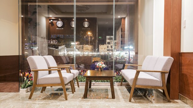 A lobby with two armchairs, a wooden coffee table, and a glass wall with a view of the city. - Quy Nhon Blue Sea Hotel (Quy Nhon Nam)