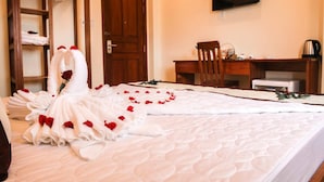 A hotel room with a neatly made bed, a wooden desk, a chair, and a television mounted on the wall. - Quy Nhon Blue Sea Hotel (Quy Nhon Nam)