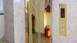 A hotel room with a marble wall, a glass elevator door, a fire extinguisher, and a wall-mounted telephone. - Quy Nhon Blue Sea Hotel (Quy Nhon Nam)