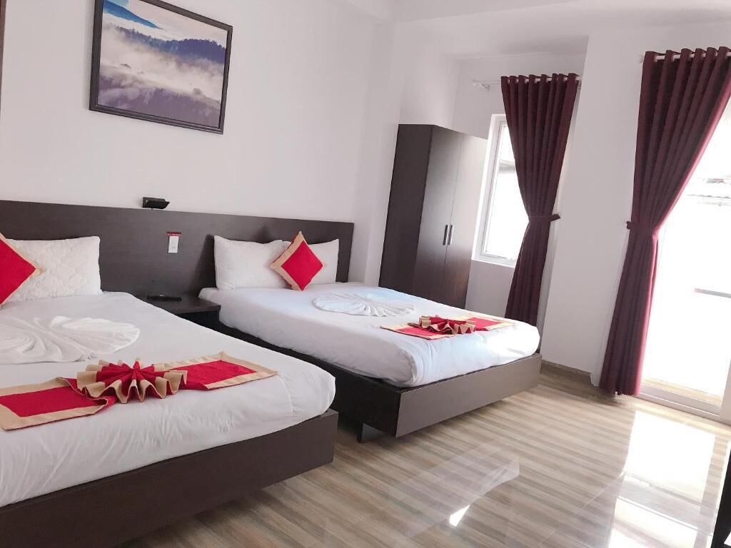 Una habitación de hotel con dos camas, un ventanal grande y un cuadro en la pared.