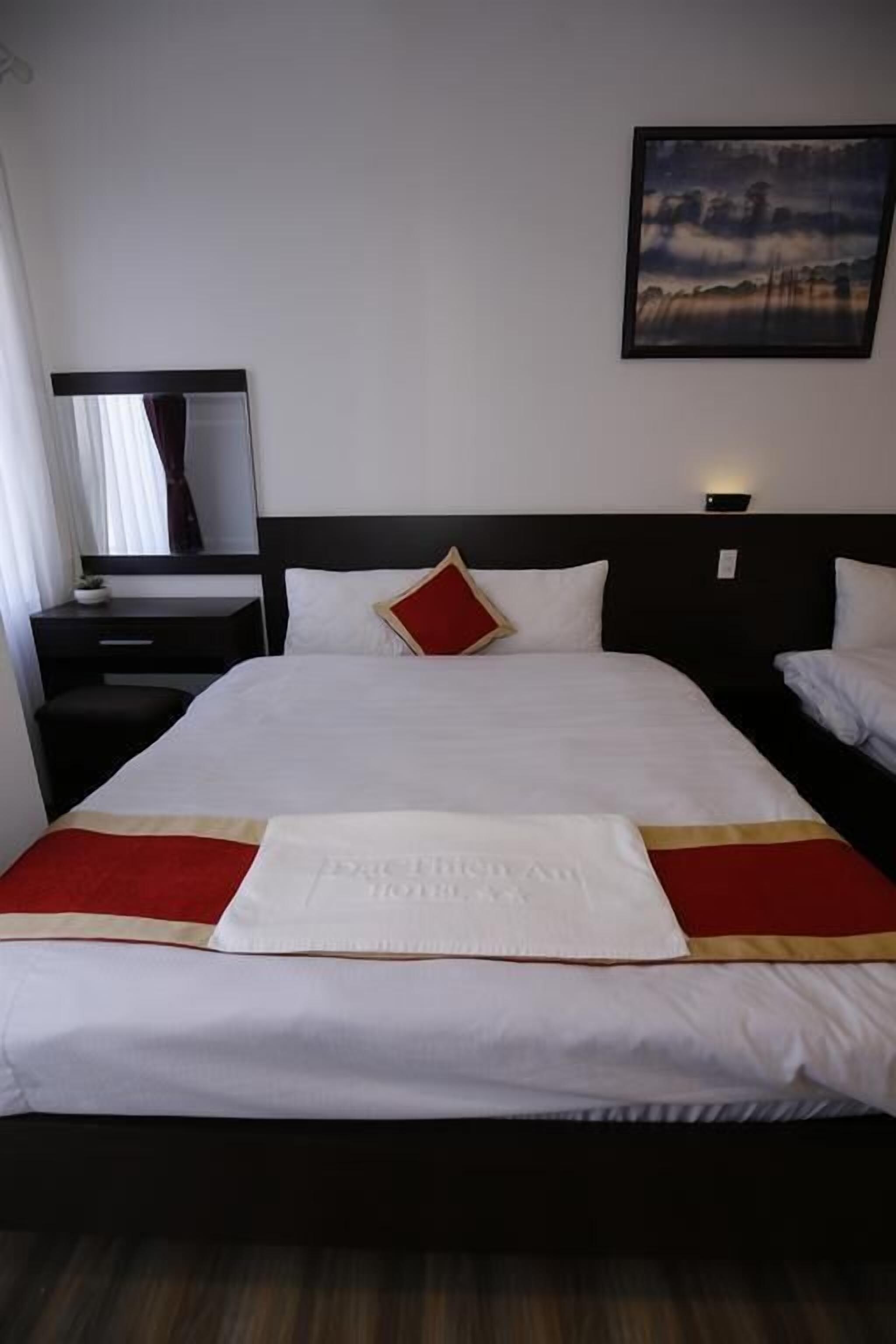 Een hotelkamer met een groot bed, een nachtkastje, een spiegel en een schilderij aan de muur.