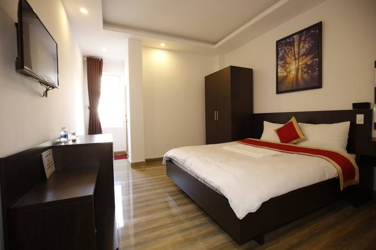 A hotel room with a bed, a desk, a wardrobe, and a television on the wall.