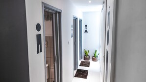 Ein Flur mit einer zur Toilette führenden Tür, Zimmerpflanzen und einer Deckenleuchte.