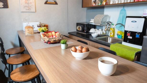 Eine Küche mit Holzausziehtisch, einer Schüssel mit Eiern, einer Kaffeetasse und verschiedenen Küchenutensilien.
