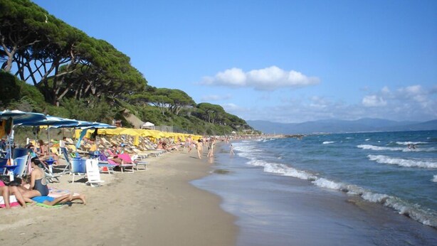 A beach with sun loungers and umbrellas, a sandy shore, and a view of the sea and distant mountains. - Borgo Valmarina (Follonica)